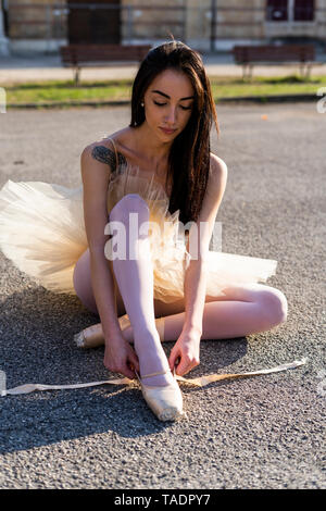 Italien, Verona, Ballerina sitzend in der Stadt setzen auf Ballett Schuhe Stockfoto