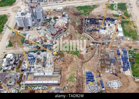 Baustelle - Luftbild eines großen Wohn- verbindung während der frühen Phasen der Konstruktion, mit Kränen und grünen Umgebung. Stockfoto