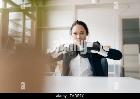 Porträt der jungen Geschäftsfrau am Schreibtisch sitzen Boxhandschuh Stockfoto