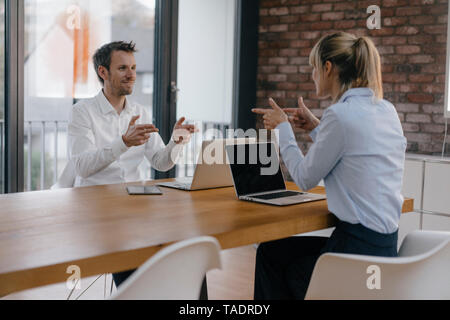 Kaufmann und Frau am Schreibtisch sitzen, Arbeiten am Laptop und zeigte mit dem Finger auf jedes andere Pistole Stockfoto