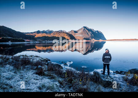 Norwegen, Lofoten, Rückansicht der Mann stand im Water's Edge im Winter bei Anzeigen suchen Stockfoto