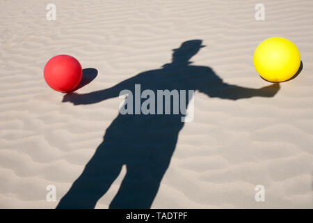 Schatten der Mann mit dem Hut und zwei Ballons in Sand Stockfoto