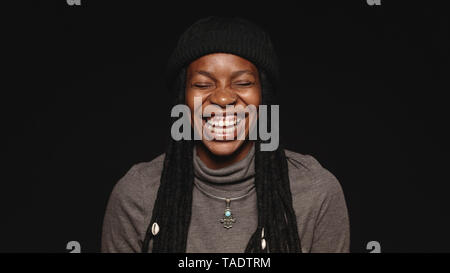 Portrait von afrikanischen Frauen in langen Dreadlocks lachend mit geschlossenen Augen. Lachende Frau auf schwarzen Hintergrund isoliert. Stockfoto