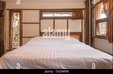 Weiß Bett im Schlafzimmer im Loft Innenarchitektur Zimmer Frontansicht. Interior Design Zimmer gehören Lampe und Klimaanlage und Fenster. Interior Design Stockfoto