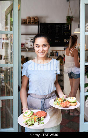 Portrait von lächelnden Kellnerin, das Frühstück serviert Stockfoto