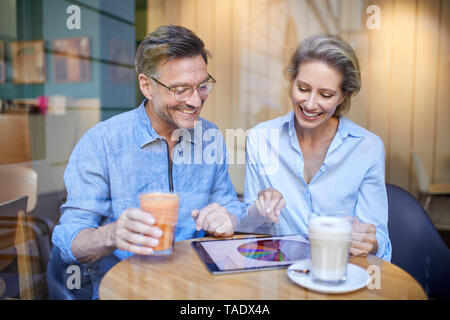 Glückliche Frau und mit Tablette in ein Cafe Mann Stockfoto