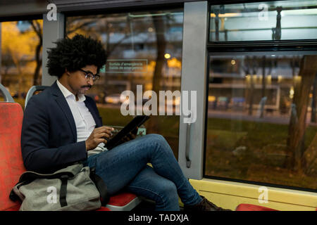 Spanien, Barcelona, Geschäftsmann, der in die Straßenbahn bei Nacht mit Tablet Stockfoto