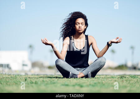 Sportliche junge frau yoga auf Rasen Stockfoto