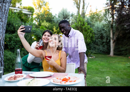 Freunde Spaß an einem Sommer Abendessen im Garten, unter selfies Stockfoto