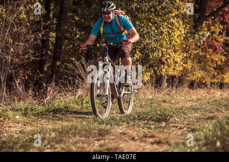 Mann reiten Mountainbike auf dem Weg durch den Wald Stockfoto