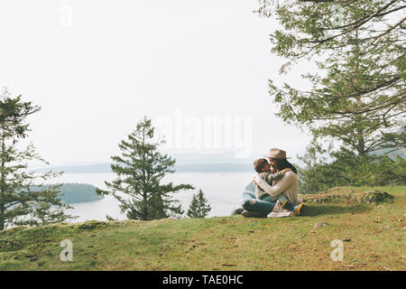 Mutter sitzt auf Gras, ihr Sohn kuscheln in der Natur Stockfoto