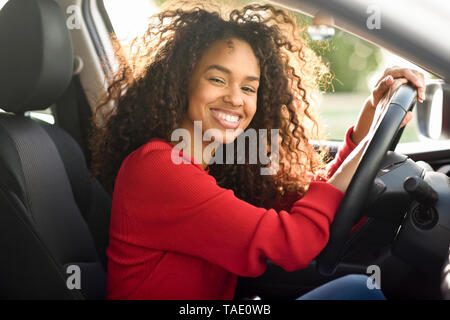 Porträt der glückliche junge Frau in einem Auto Stockfoto