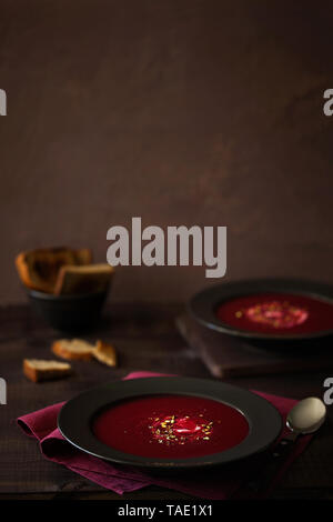 Gesunde rote Rüben Suppe oder Smoothie mit gehackten Pistazien und saure Sahne in die schwarze Platte im rustikalen Stil mit Platz für Text kopieren eingerichtet Stockfoto