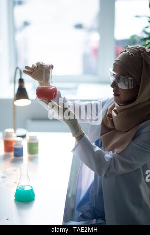 Auf der Suche nach Chemie. Junge weibliche Chemiker im Labor saßen und bei chemischen Glas mit chemischen Stockfoto