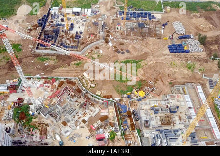 Baustelle - Luftbild eines großen Wohn- verbindung während der frühen Phasen der Konstruktion, mit Kränen und grünen Umgebung. Stockfoto