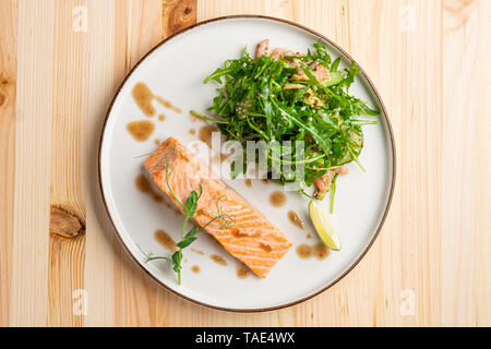 Gedünsteter Lachs mit Rucola und Garnelen garnieren Stockfoto