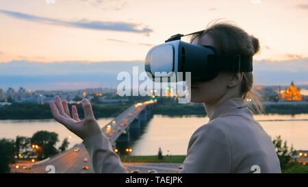 Frau verwendet virtuelle Realität Gläser in der Stadt nach Sonnenuntergang Stockfoto