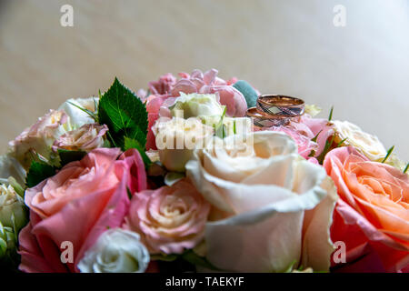 Trauringe auf den Strauß Rosen. Trauringe auf Brautstrauß mit bunten Rosen. Blumenstrauß der Braut mit Blumen und Gold Ringe. Stockfoto