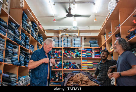 Horizontale Porträt eines westlichen Touristen auf einem T-Shirt zu einem Bekleidungsgeschäft in Indien versuchen. Stockfoto