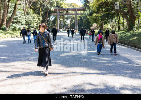 Tokyo, Japan - 3. April 2018: Meiji Schrein Tor Eingang mit grüner Baum Wald im Frühling und viele Menschen zu Fuß auf Kies Steinweg Straße Stockfoto