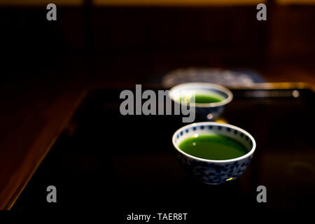 Traditionelle japanische Cups mit Matcha oder Mulberry Green Tea in Ryokan mit Schwarz lackiertem Holz Tisch Stockfoto