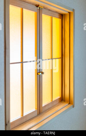 Traditionelle japanische Haus oder Ryokan mit Nahaufnahme des geschlossenen Fensters Tür mit transparentem Glas und gelbes Licht Stockfoto