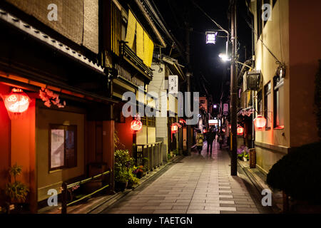 Kyoto, Japan - 9. April 2019: Alley bunte Straße in Gion Distrikt Schmal in der Nacht mit Menschen und Beleuchtete rote Laternen Stockfoto