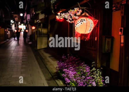 Kyoto, Japan - 9. April 2019: Alley bunte Straße in Gion Distrikt schmale Nachts mit Nahaufnahme des beleuchteten rotes Papier Laternen und Bokeh backgrou Stockfoto