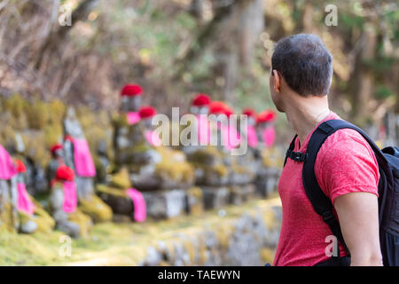 Nikko, Japan und junge Mann an Jizo Statuen in den berühmten Kanmangafuchi Abgrund in der Präfektur Tochigi in Japan im Frühjahr mit Moss Stockfoto