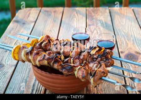 Hot Schweinefleisch Grillen am Grill mit Gewürzen und Gläser Rotwein zubereitet, auf hölzernen Tisch. Stockfoto