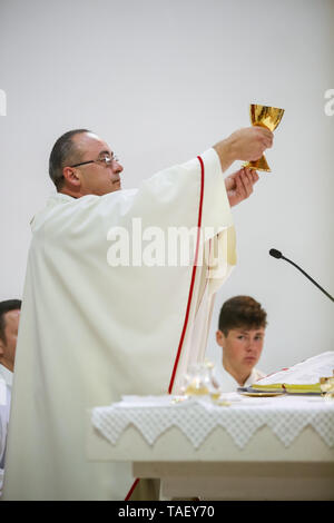 Zagreb, Kroatien - 11. Mai 2019: ein Priester holding Kelch oben hob den Kopf auf dem Altar während die erste heilige Kommunion, die Messe in der Kirche von St. Niko Stockfoto