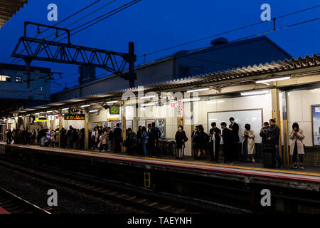 Kyoto, Japan - 11. April 2019: Bahnsteig in tofukuji mit Menschen warten auf shinkansen und salaryman Geschäftsmänner auf Pendeln in dunklen sogar Stockfoto