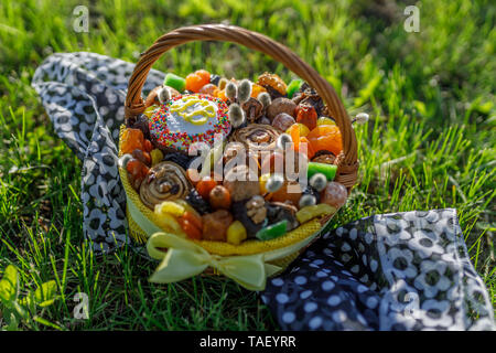 Korb mit Ostern Kuchen, getrocknete Früchte und Nüsse auf dem grünen Rasen Stockfoto