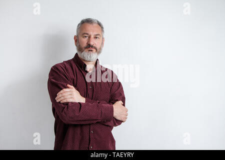 Brustbild eines schweren Grauhaarige bärtigen Mann in einem Burgund Shirt auf einem weißen Hintergrund. Stockfoto