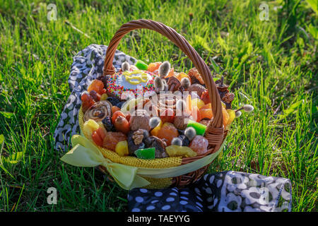 Korb mit Ostern Kuchen, getrocknete Früchte und Nüsse auf dem grünen Gras im Garten Stockfoto