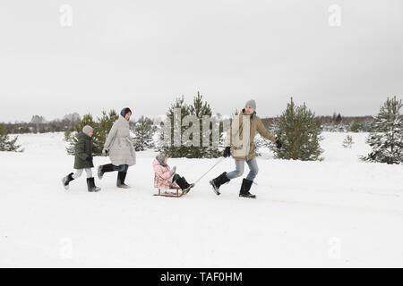 Familie Spaß mit Schlitten in der verschneiten Landschaft Stockfoto