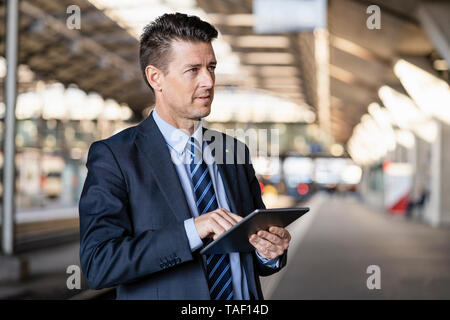 Geschäftsmann mit Tablet am Bahnhof Stockfoto