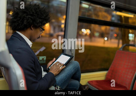 Spanien, Barcelona, Geschäftsmann, der in die Straßenbahn bei Nacht mit Tablet Stockfoto