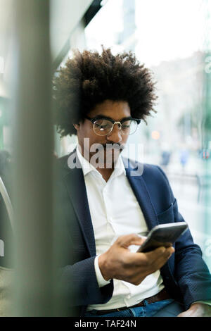 Spanien, Barcelona, Geschäftsmann, der in einer Straßenbahn mit Handy Stockfoto