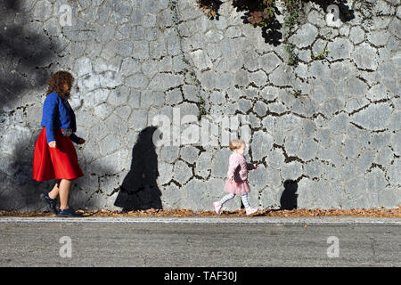 Kleines Mädchen mit ihrer Mutter an einer Steinmauer Stockfoto