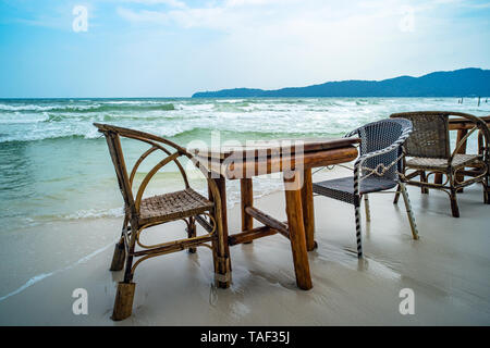 Bambus Tisch und Stühle aus Holz in leeren Cafe neben Meer Wasser in tropischen Strand. Close Up. Insel Koh Phangan, Thailand Stockfoto