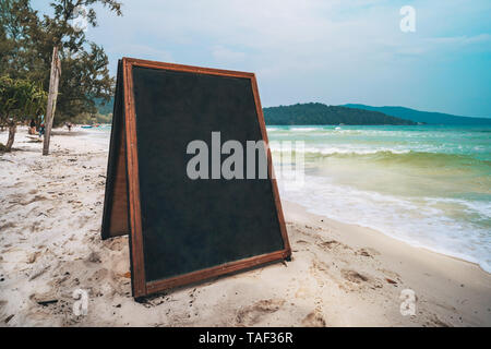 Leeres Menü Board am Strand. leere Plakatwand für die Beschriftung auf dem Hintergrund der See mit türkisfarbenem Wasser und einem wunderschönen Strand auf der Insel. Stockfoto