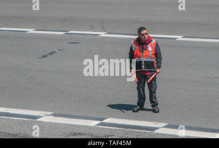 New York, 15.05.2019: Airport Ground Crew Mitglied leitet ein Verkehrsflugzeug auf der Start- und Landebahn am Flughafen LaGuardia. Stockfoto