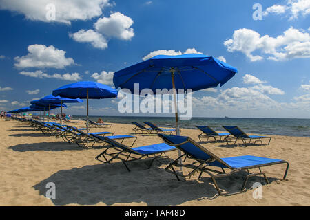 Blaue Schirme und Liegen am Strand bräunen installiert. Stockfoto