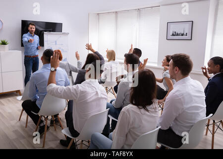 Männliche Moderator Fragen zu seinem Kollegen heben die Hände während des Seminars Im Büro Stockfoto