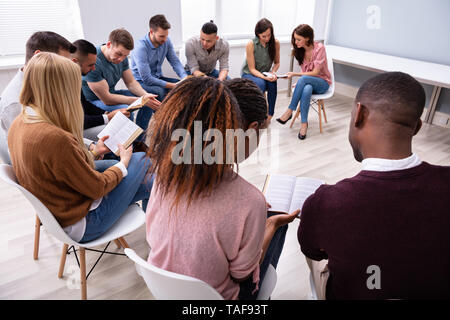 Gruppe Junger multi-ethnischen Menschen Lesen der Bibel zusammen Stockfoto