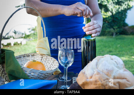 Frau entfernen von Cork aus einer Flasche Wein für eine Feier mit Brot, Wein und Obst Stockfoto