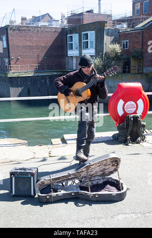 Gitarre Straßenmusikant gegen die Elemente auf der Prinz von Wales Pier in Falmouth, Cornwall Großbritannien gekleidet Stockfoto