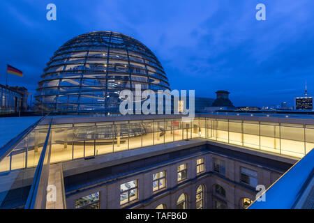 Beleuchtete Glaskuppel auf dem Reichstag (Deutscher Bundestag) Gebäude in Berlin in der Dämmerung. Fernsehturm Fernsehturm im Hintergrund. Stockfoto