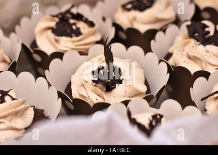 Schöne Schokolade Sahne cupcakes in ein weißes Kästchen mit einem Seil an einem konkreten Hintergrund gebunden Stockfoto